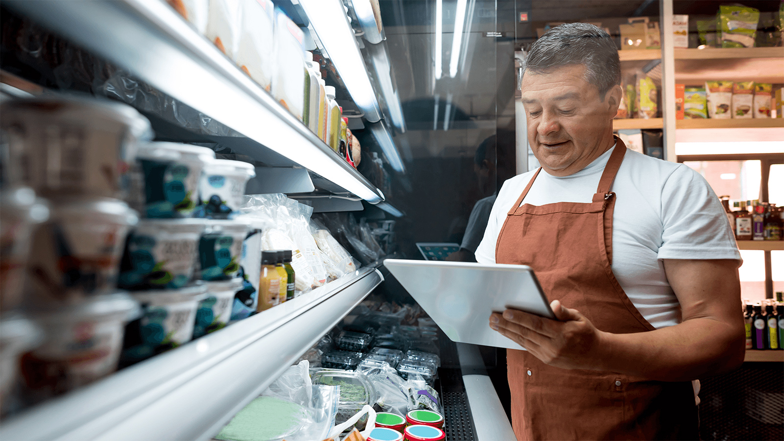 Man taking inventory of a shelf in a grocery store.