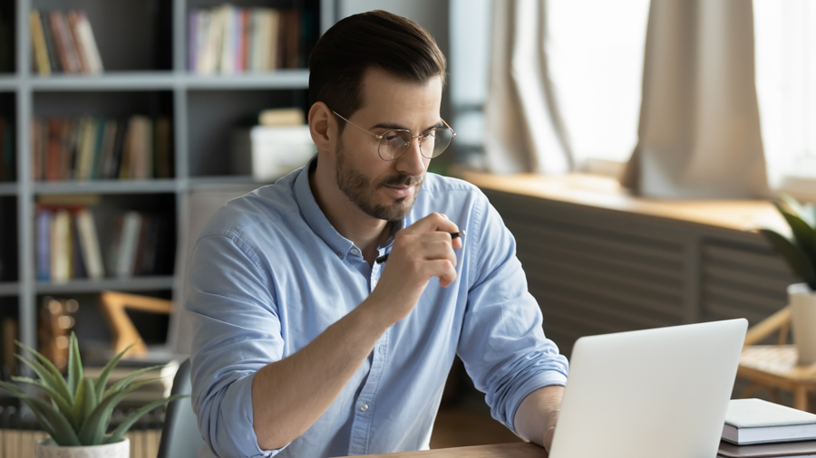 Man sitting at a table looking at a laptop