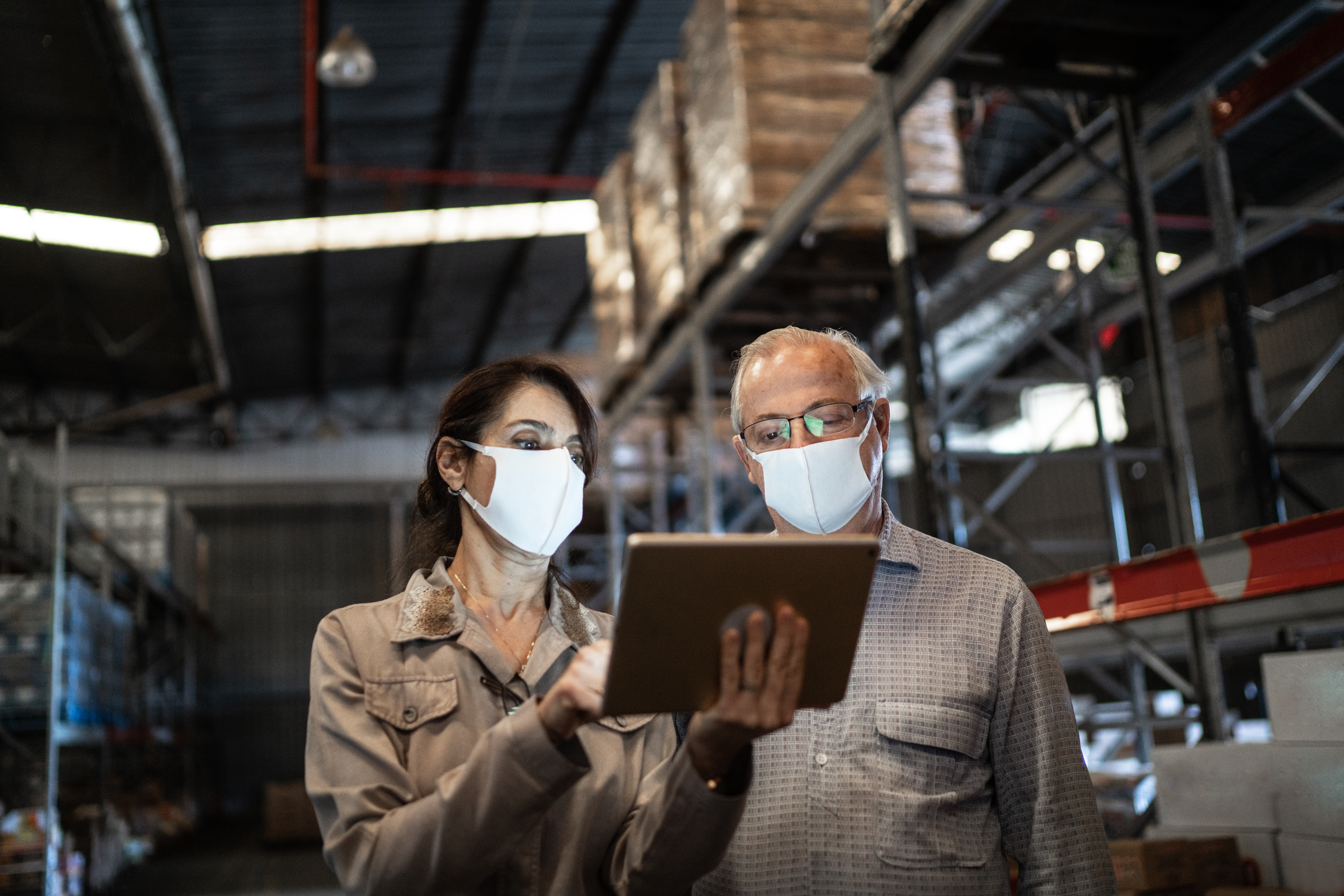 A man and woman in a warehouse reading a tablet
