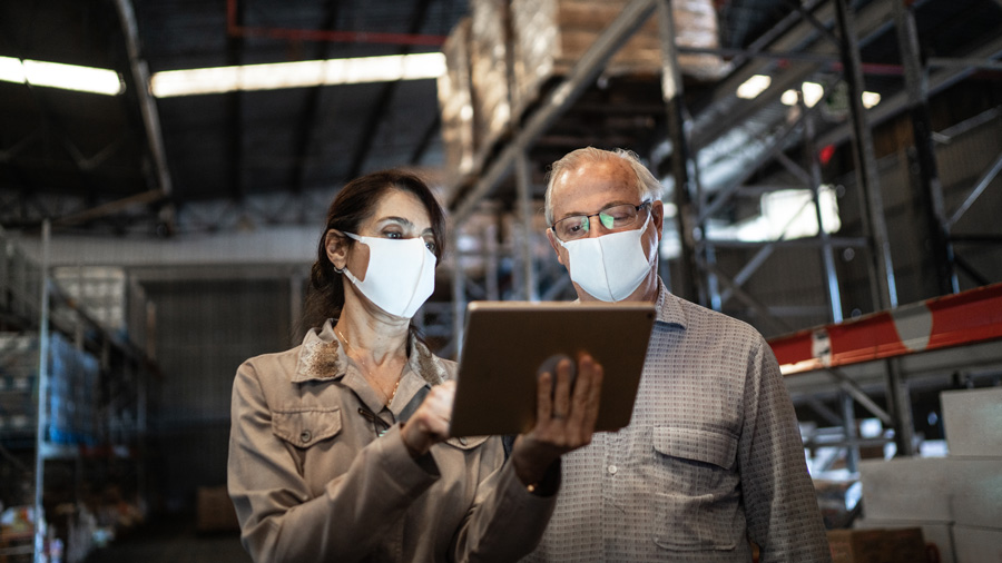 A man and woman in a warehouse reading a tablet
