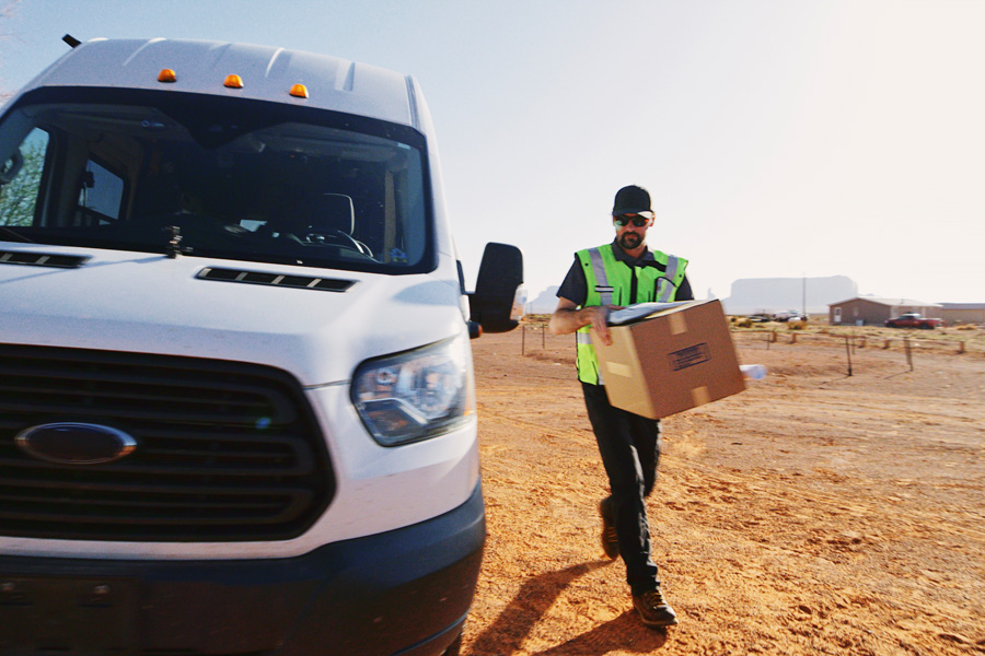 A delivery person walking around a van