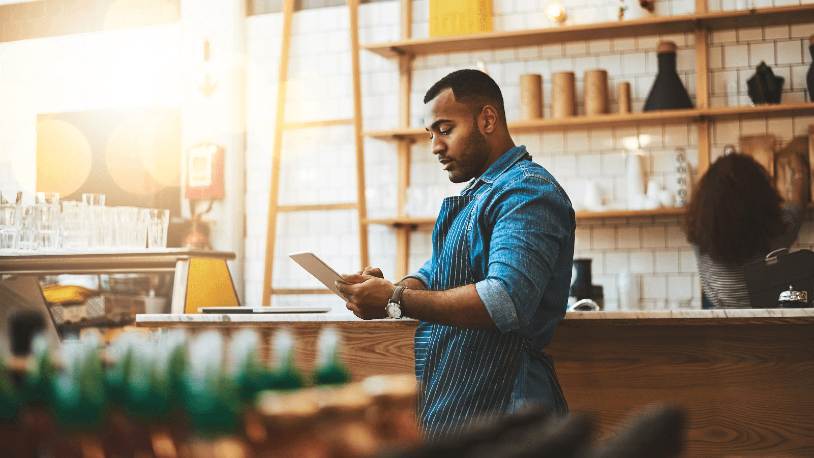 Man using a tablet in front of a coffee bar.