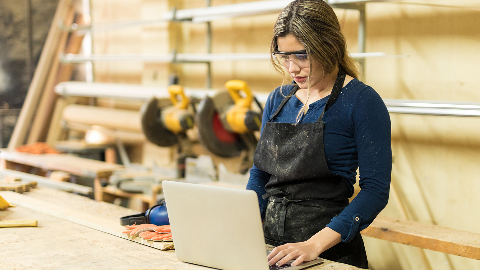 Woman using laptop in a woodshop.