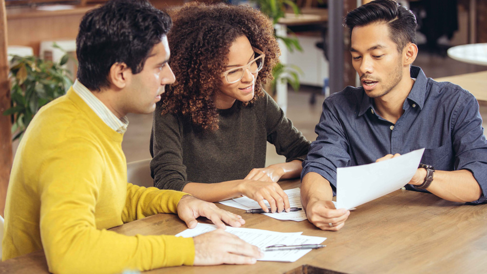 People sitting together at a table talking about a document.