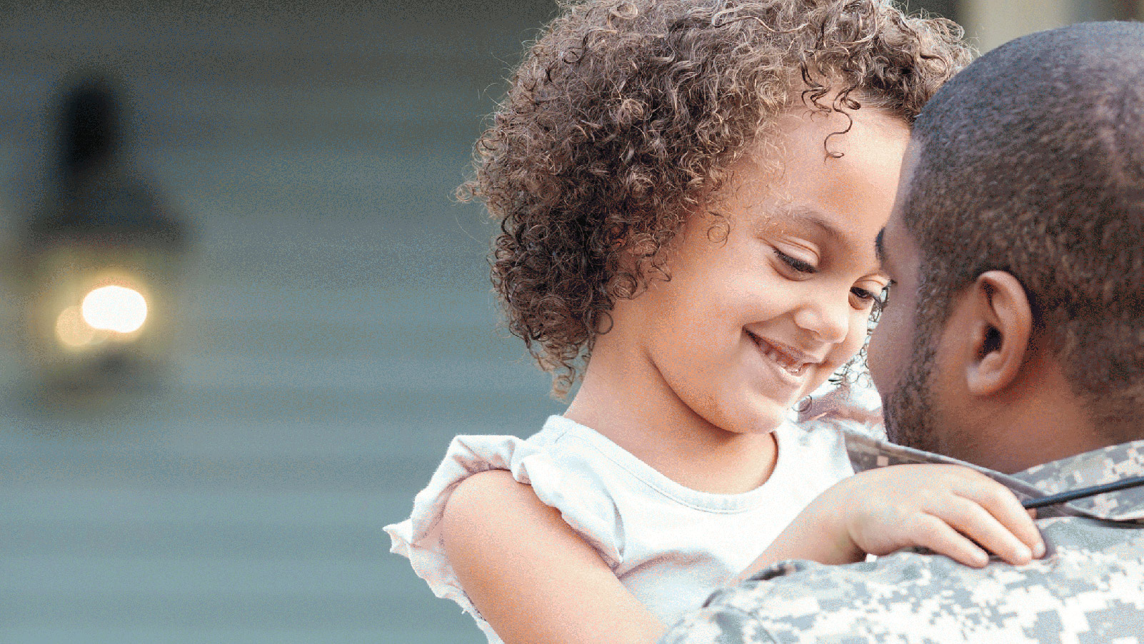 Little girl smiling and hugging her father as he comes home from military service.