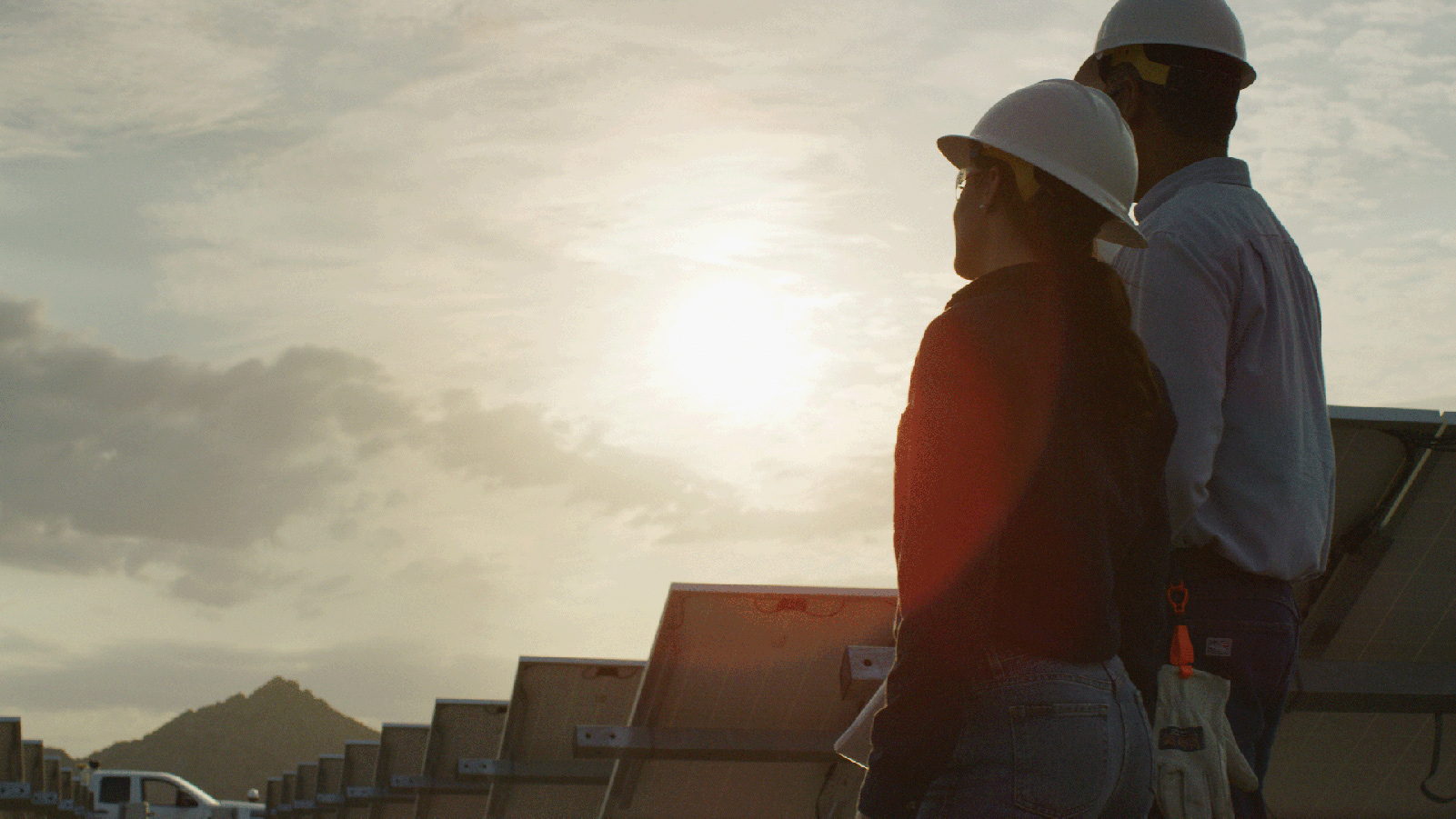 Two APS employees standing in a solar field, looking off into the distance.
