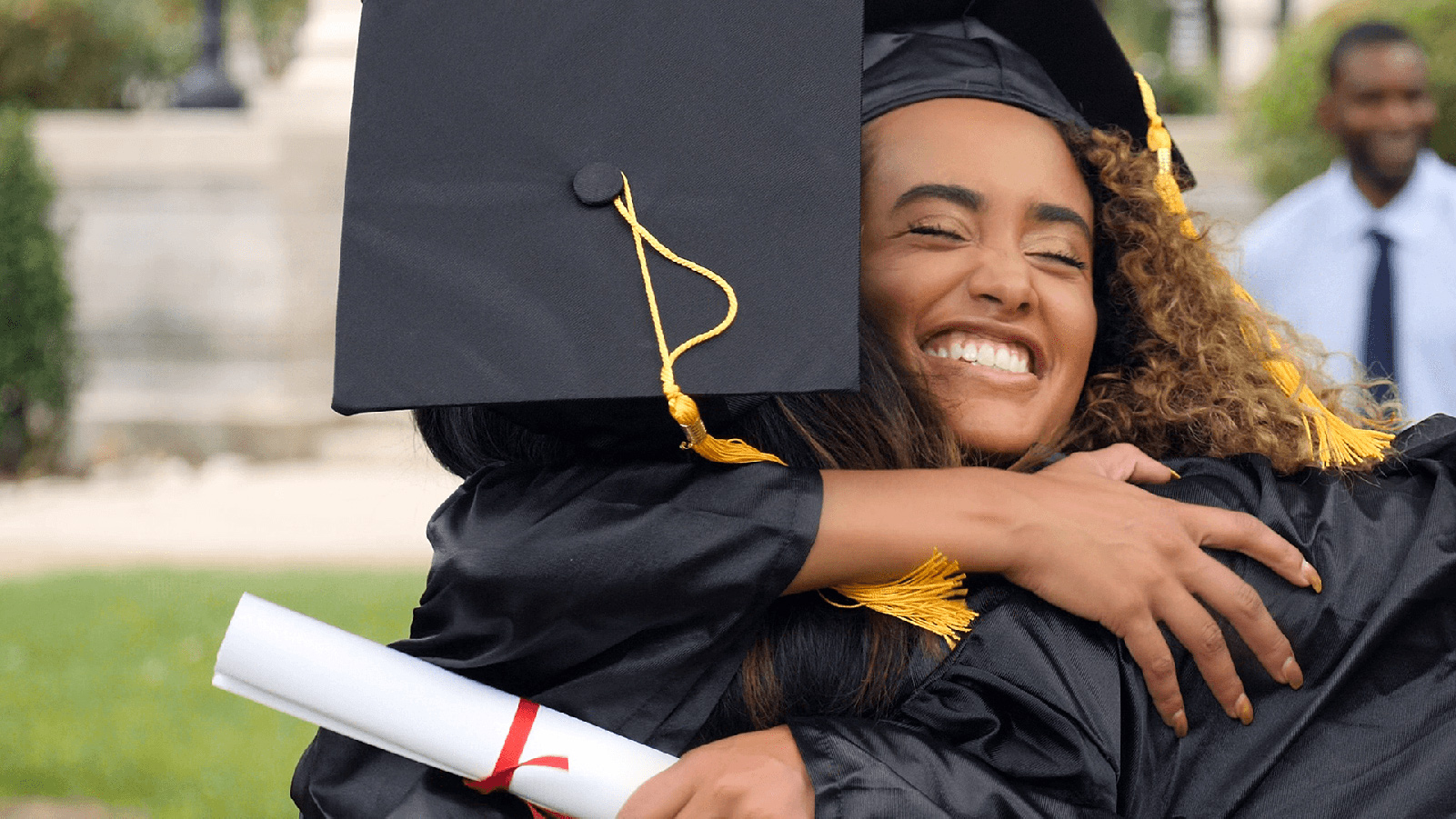 Two college graduates hugging in their caps and gowns.