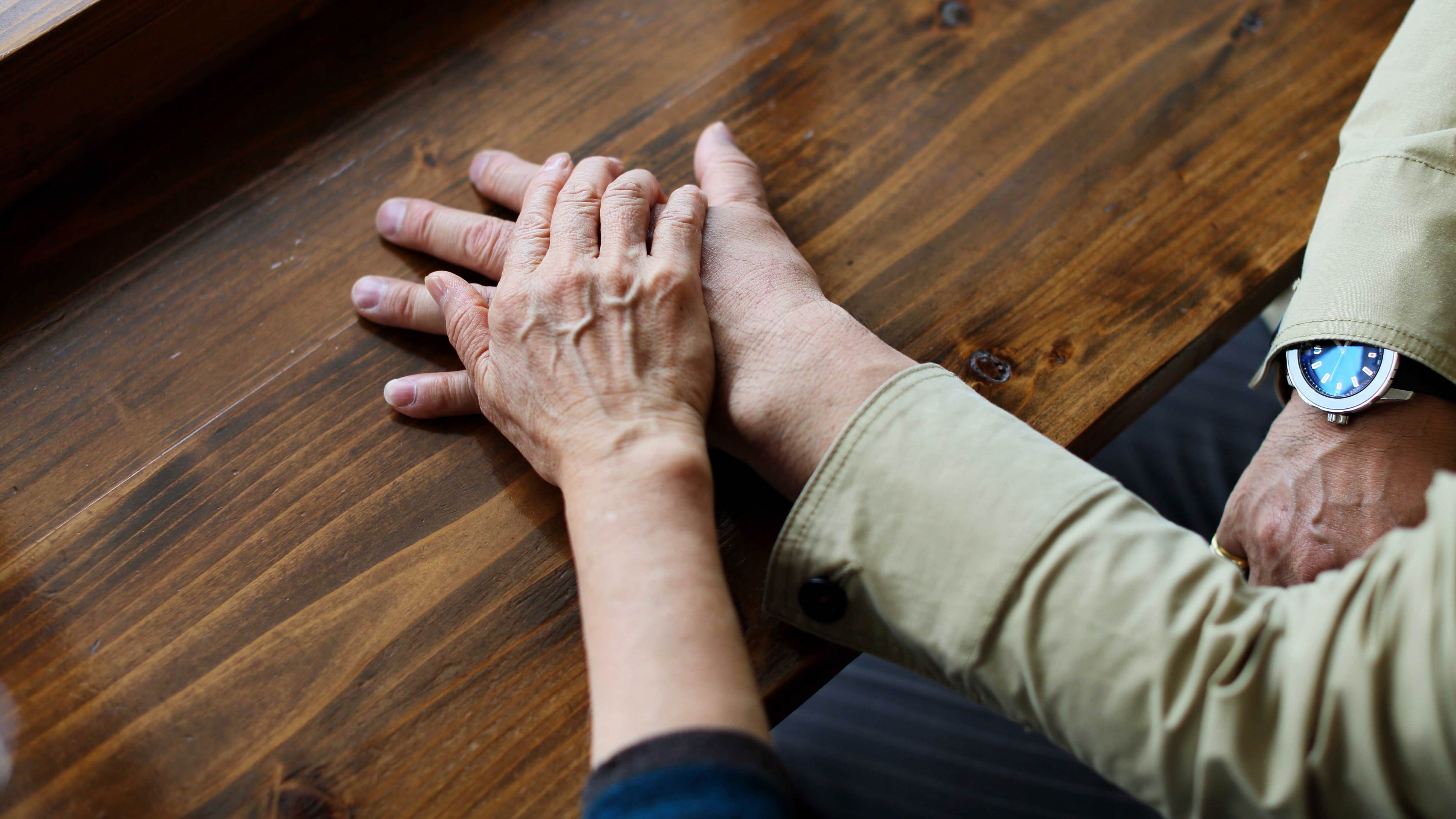 Two people holding hands across a table.