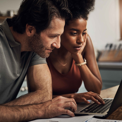 Couple at table looking at bills on a laptop