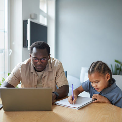 Man using laptop while son does homework