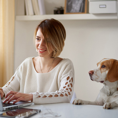 Woman using a laptop next to a dog