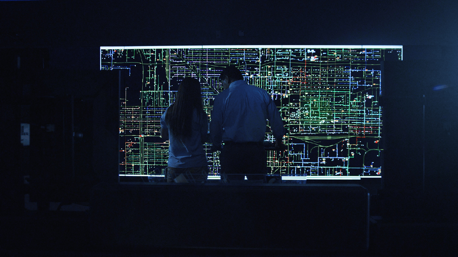 Two APS employees looking at a grid map in a dark room.