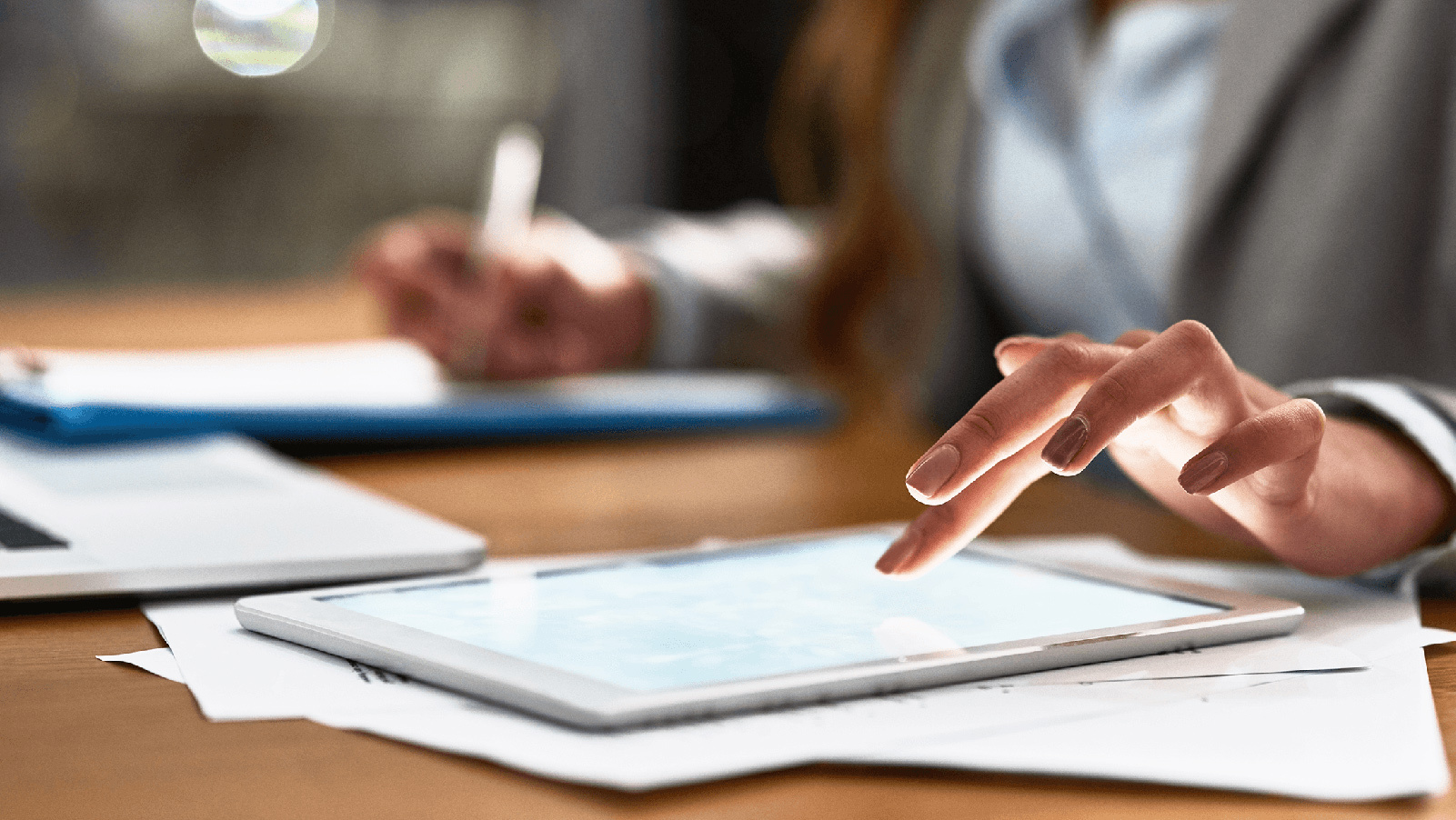 Woman working on her tablet and taking notes.