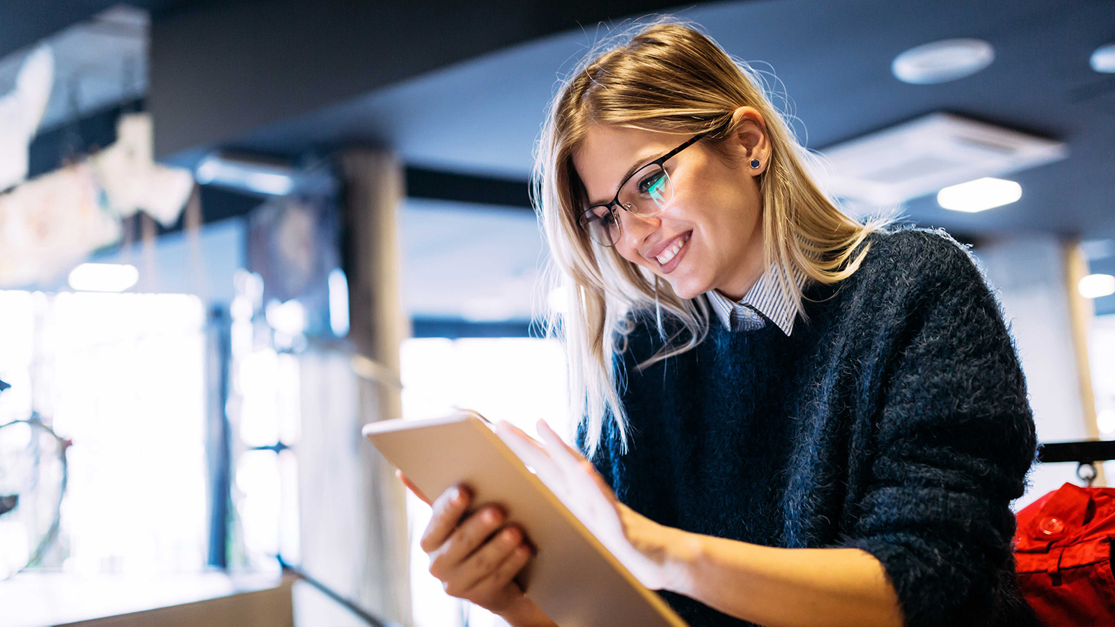 Woman in glasses smiling and using a tablet.