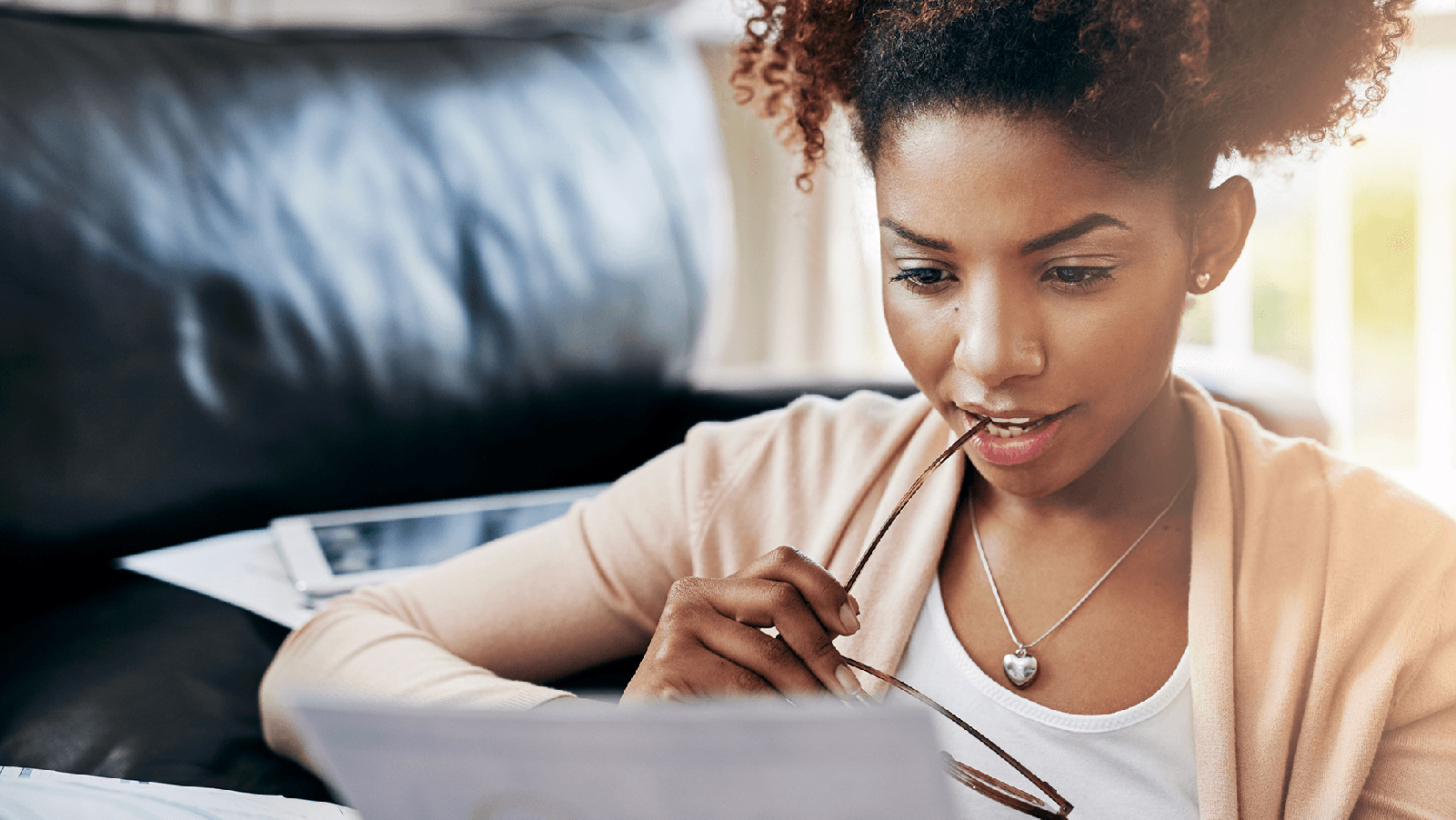 Woman holding her glasses and reading paperwork.