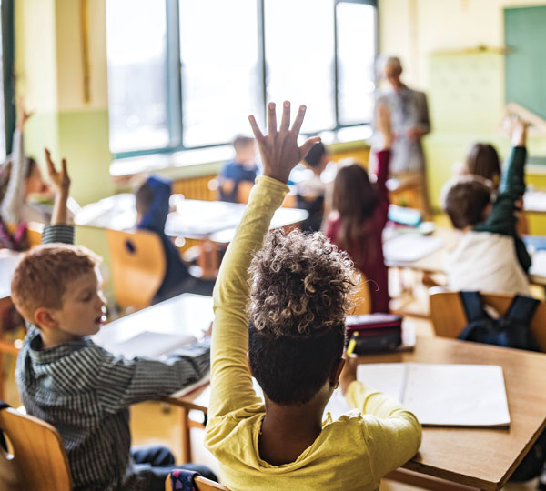 kids in classroom with hands raised