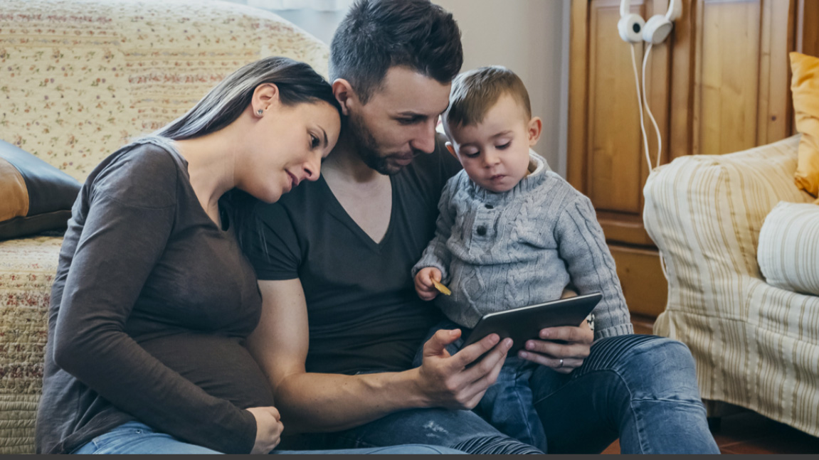 Pregnant family looking at tablet in living room