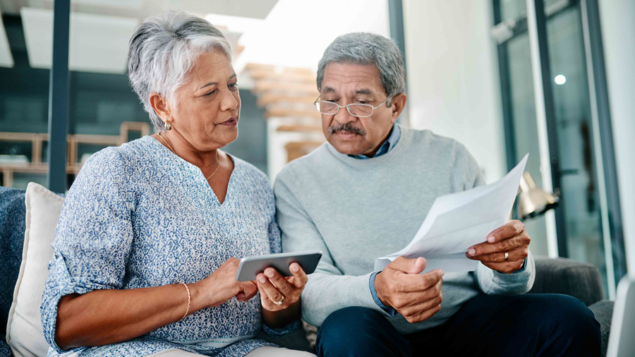 An elderly couple sitting together reviewing document and phone 