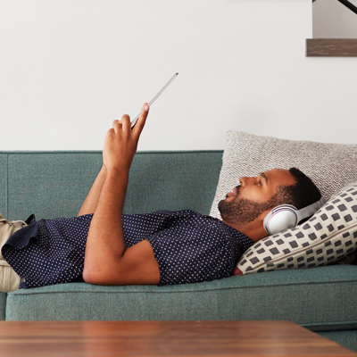 Man laying on couch reading tablet