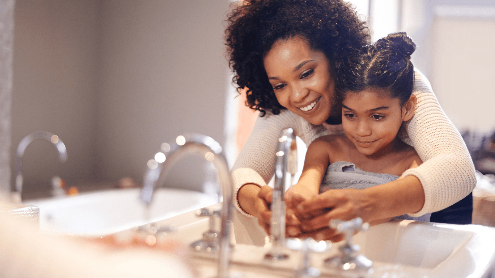 Mother and daughter washing hands in a sink