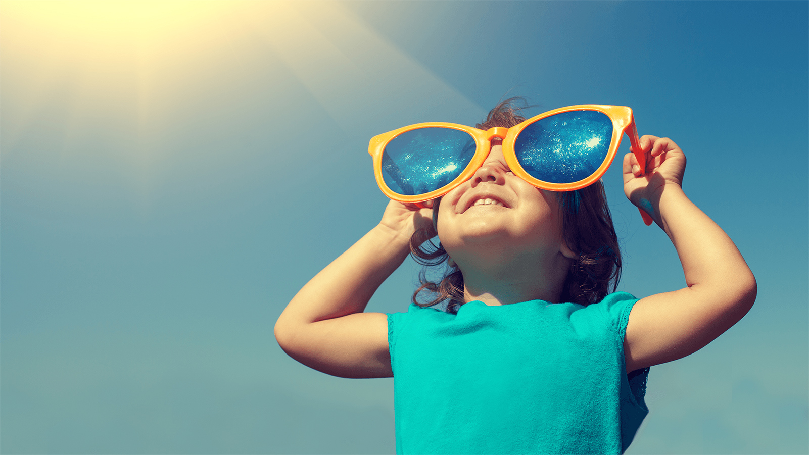 Little girl wearing oversized sunglasses on a bright sunny day.