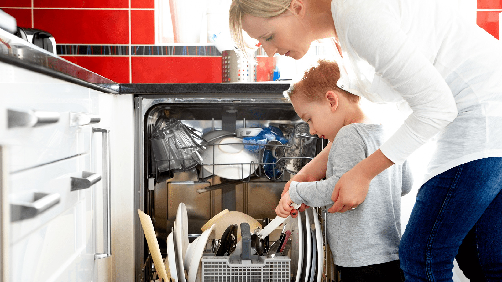 Little boy helping his mother load the dishwasher.