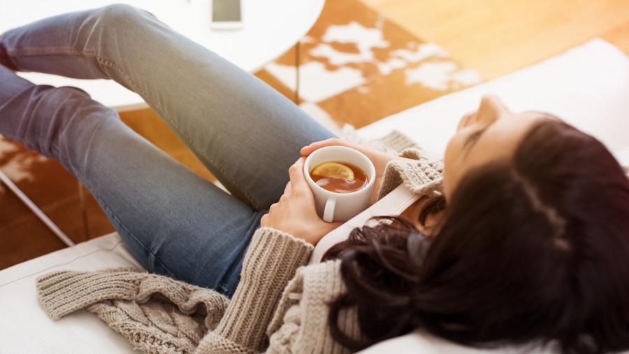 Woman relaxing on the couch with a cup of tea.