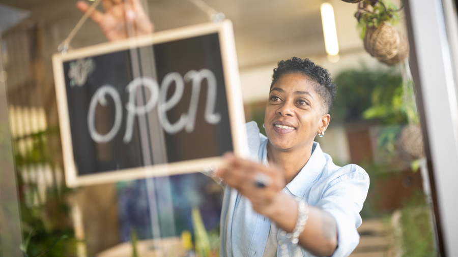 Woman turning around an open sign on a glass door