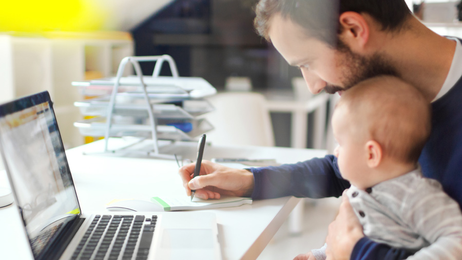 Father doing bills at table with son in lap