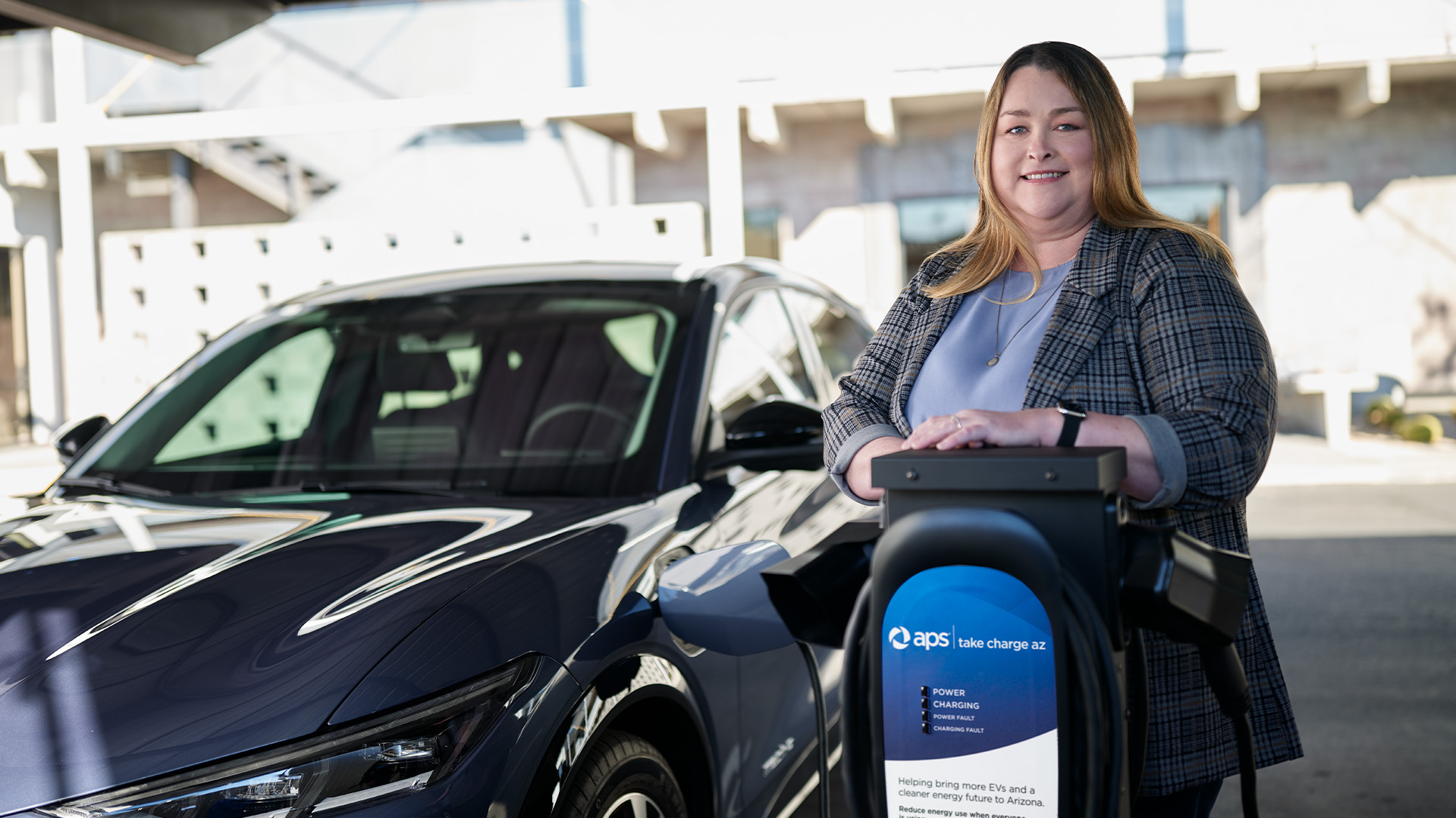 Woman standing next to an EV and charger