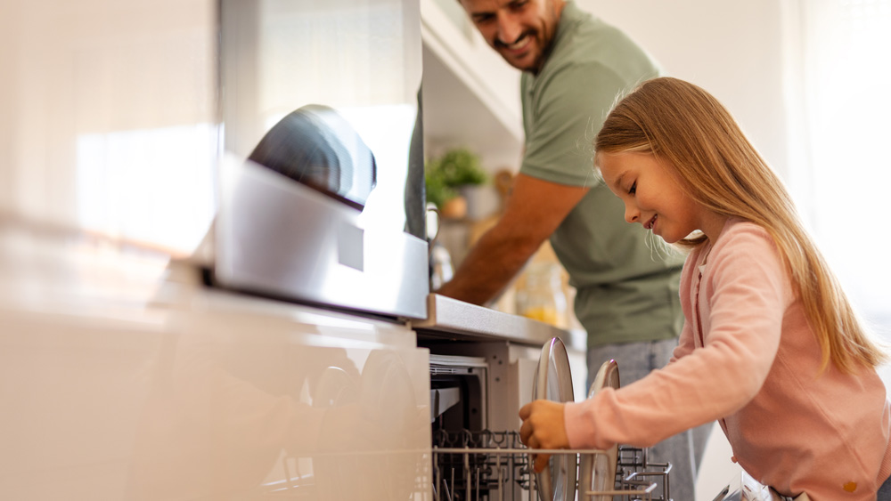 Father and daughter loading dishwasher