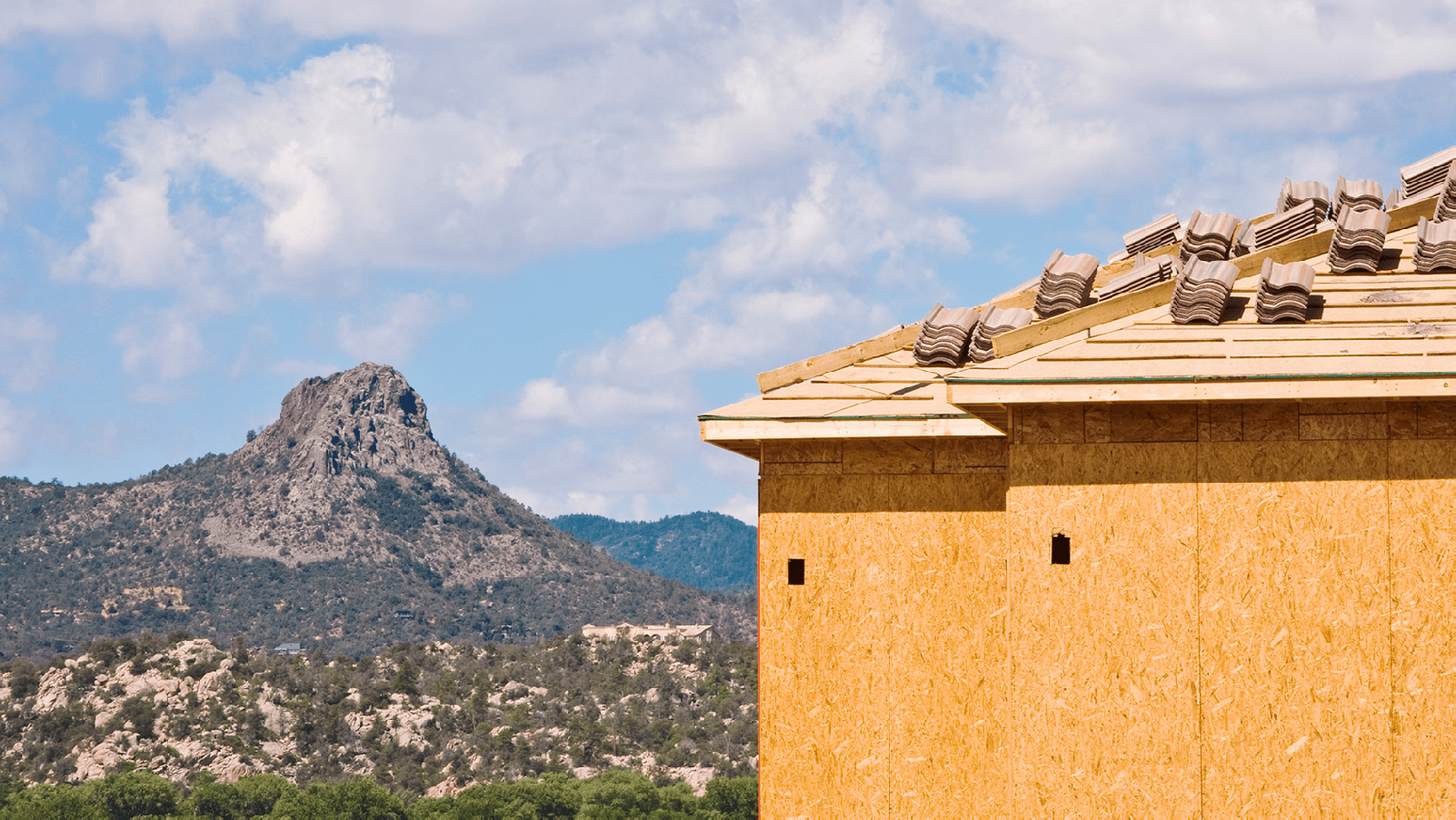 New home with unfinished roof next to a mountain