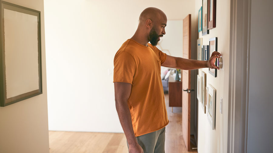 Man adjusting the thermostat in his hallway