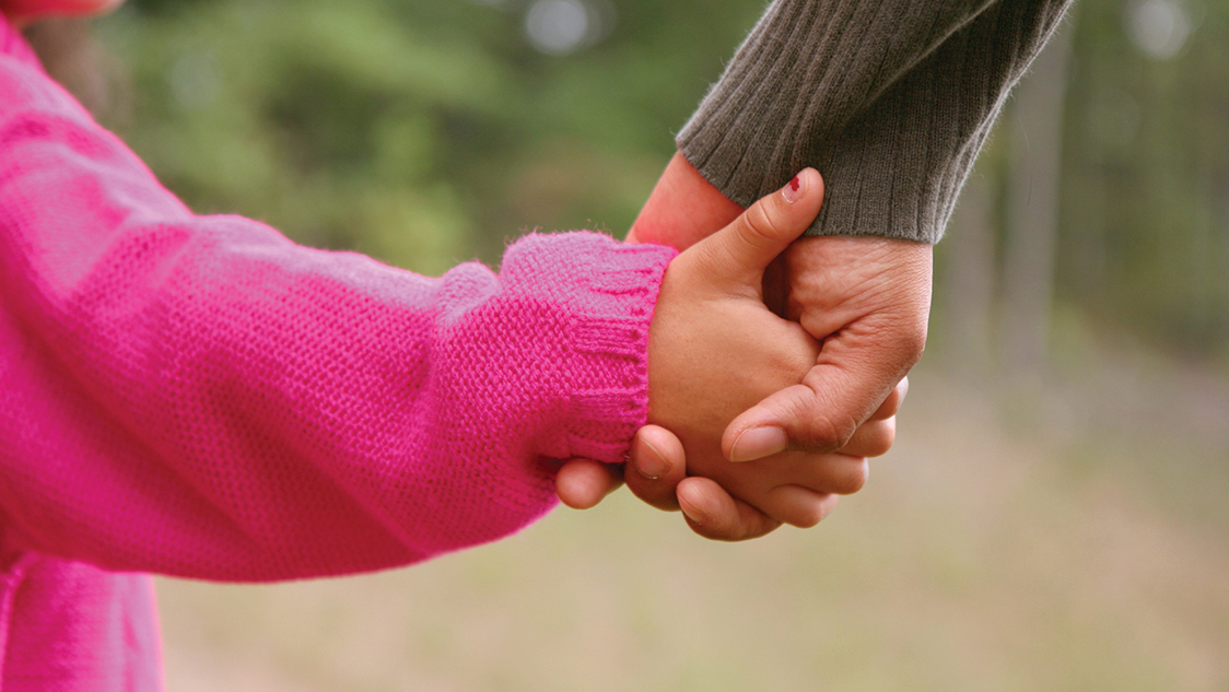 Mom holding hands with her daughter.