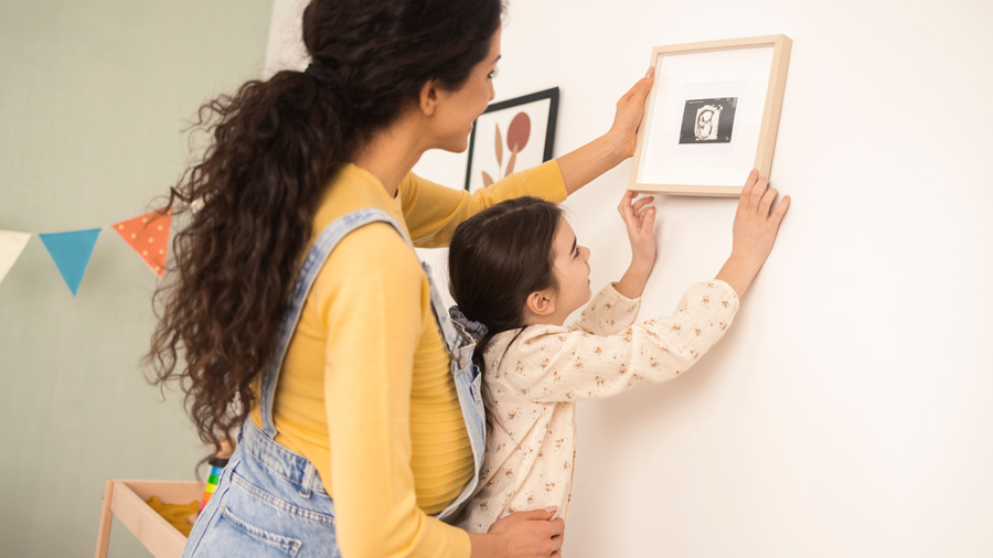 Mom and daughter hanging pictures